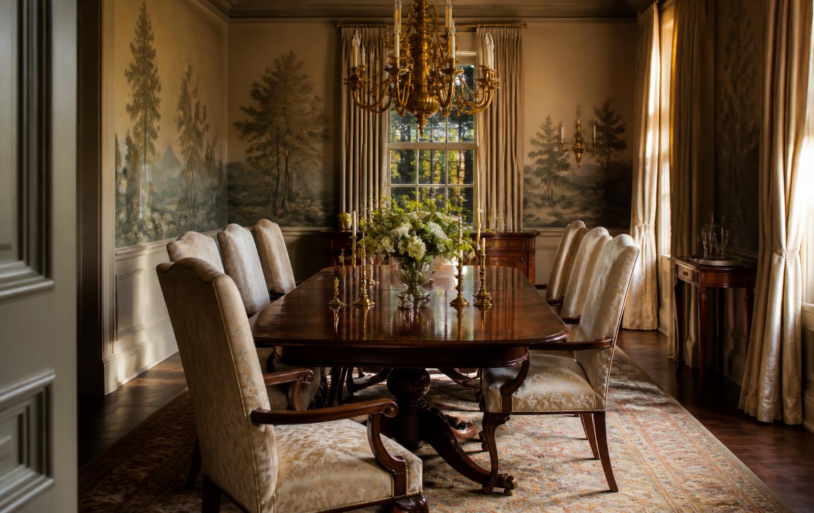 A formal dining room with scenic wallpaper, walnut table, and antique brass chandelier