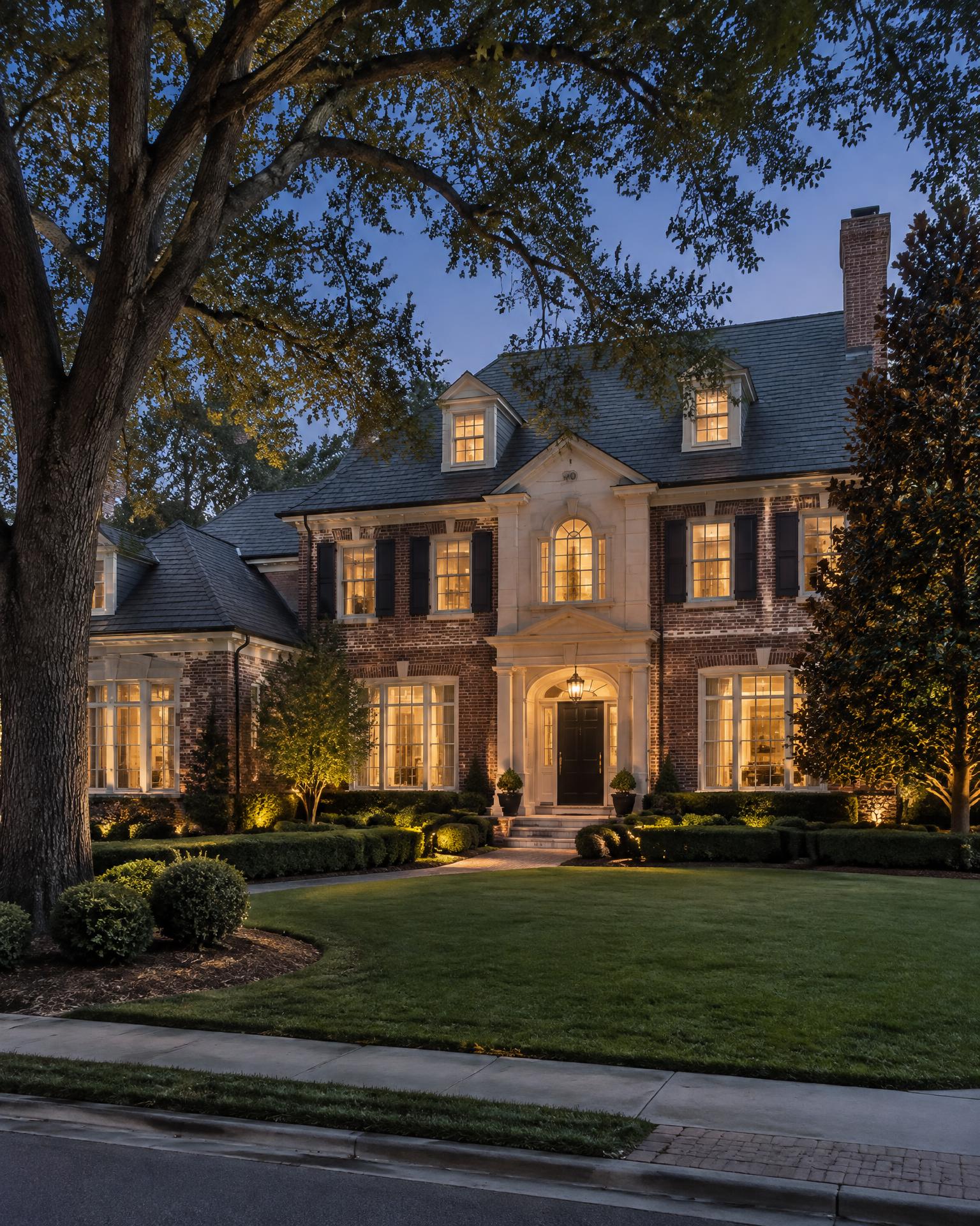 Luxury estate home exterior at dusk with warm interior light